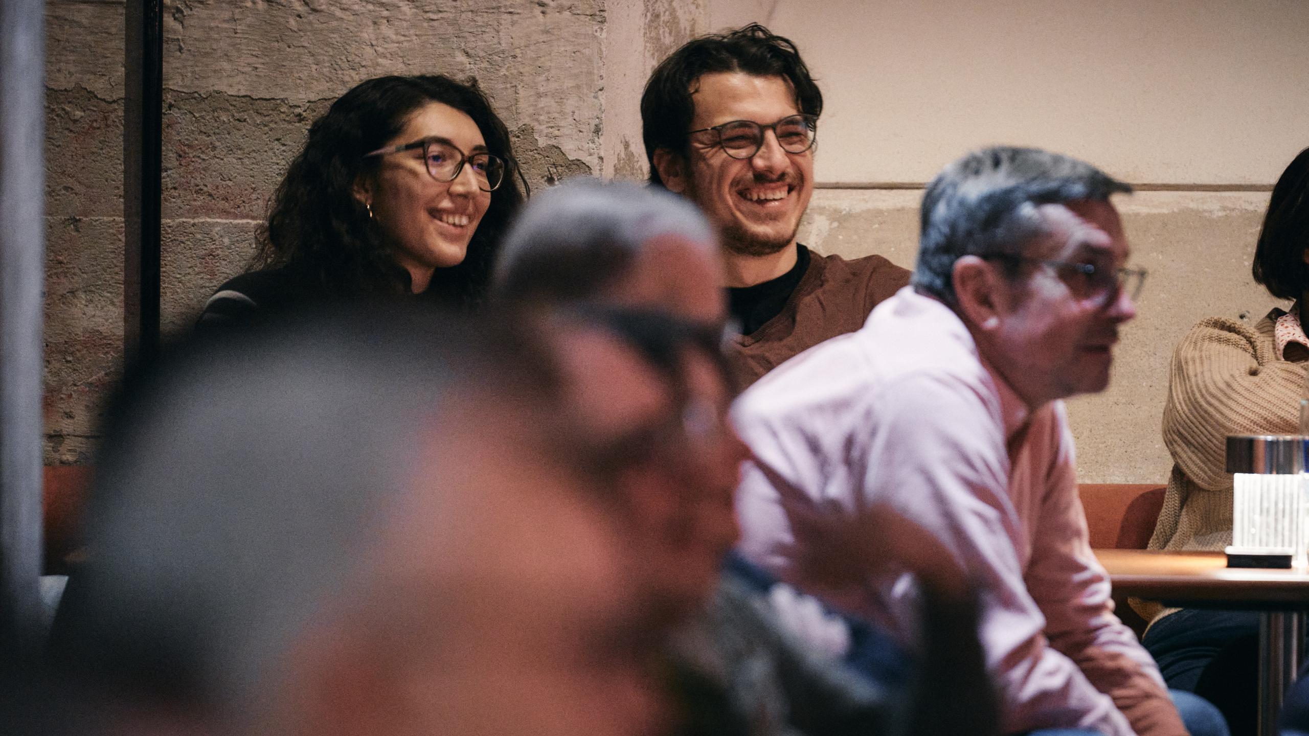 Gäste lachen und genießen eine Comedy-Show im Lucky Punch Comedy Club im Bergson-Kulturareal in München. Nahaufnahme von zwei fröhlichen Zuschauer:innen in gemütlicher Atmosphäre.