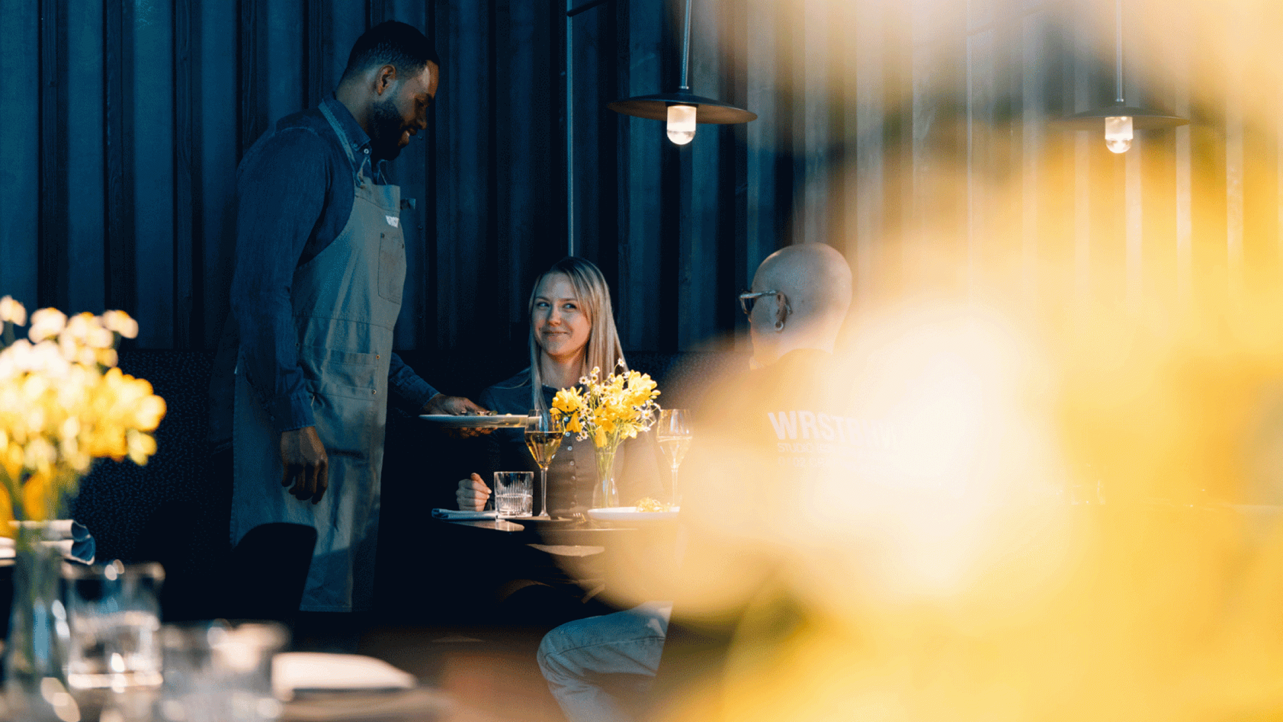 Kellner serviert lächelnden Gästen im Restaurant Zeitlang des Bergson ihr Essen