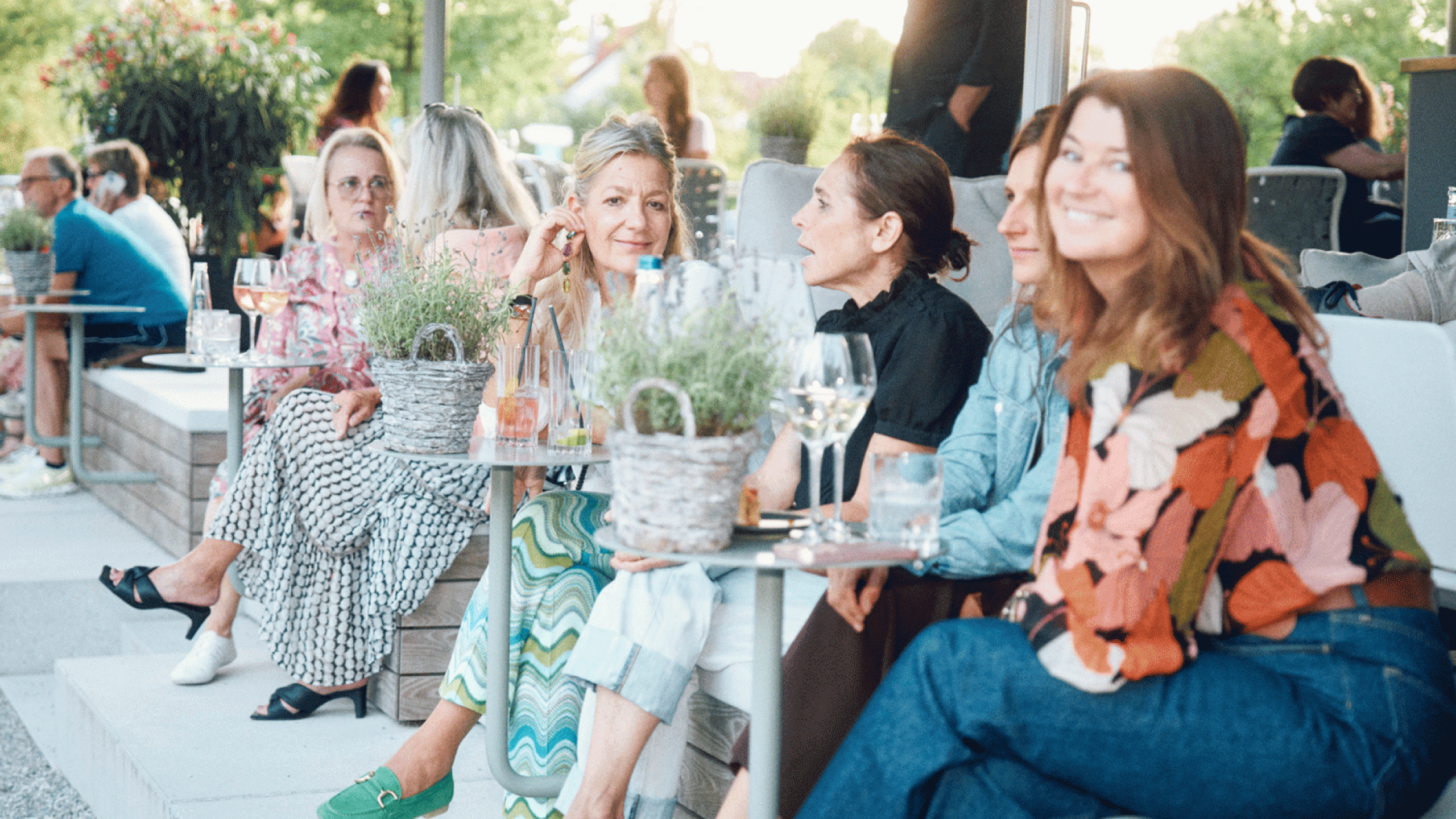 Gäste sitzen bei sommerlichem Ambiente auf der Außenterasse im Bergson Kunstkraftwerk