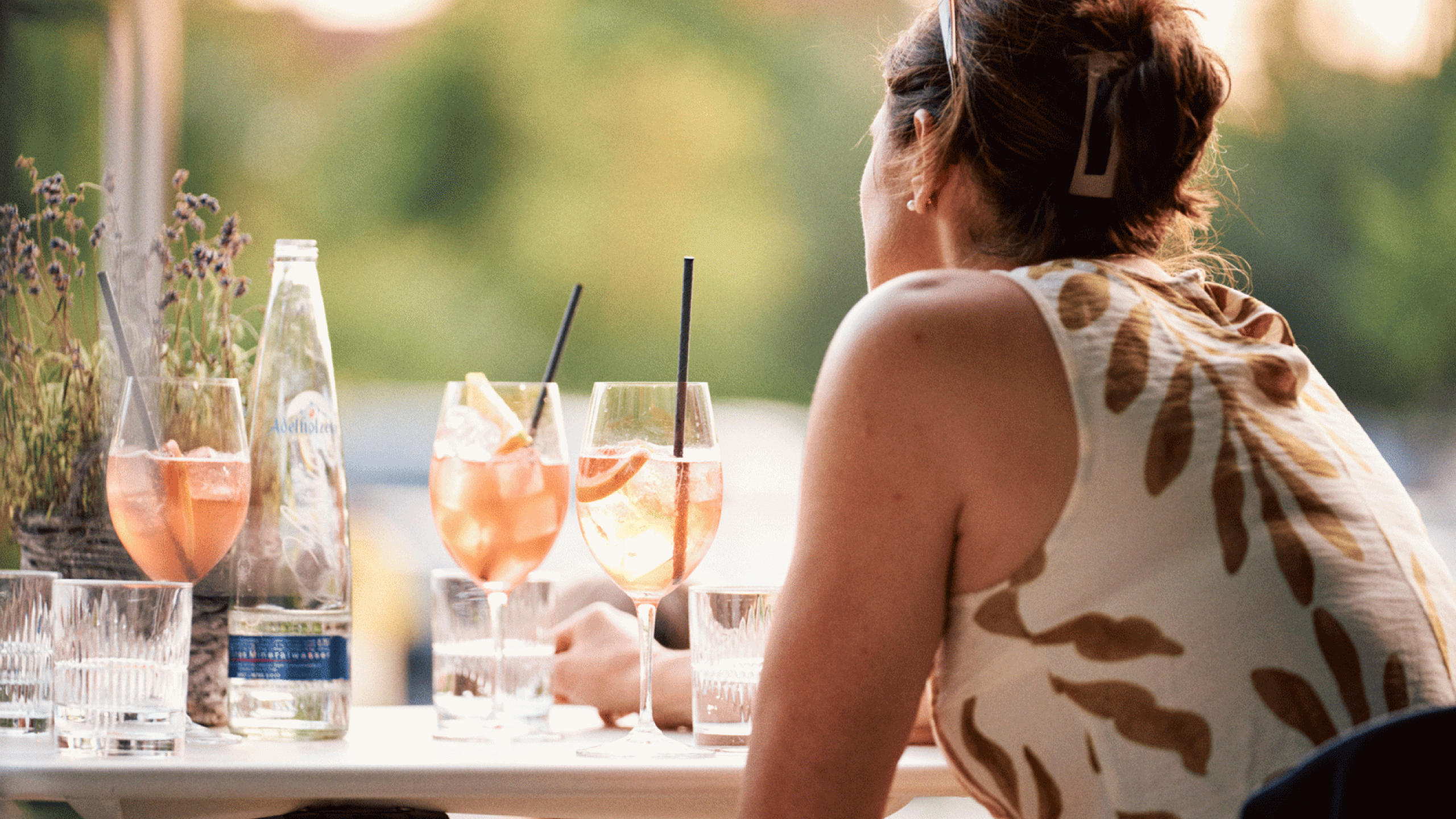 Gast sitzt bei sommerlichem Ambiente auf Außenterasse mit Aperol Spritz